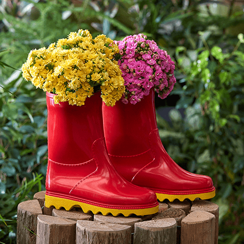 Red gumboots with yellow soles filled with pink and yellow flowers.