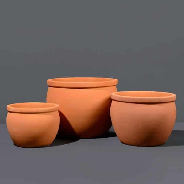 Three plain and round terracotta pot plants in different sizes, set against a dark background.