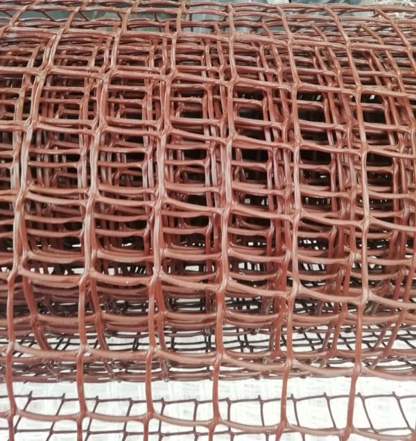 A close-up view of a rolled-up length of copper wire mesh with a fine, square grid pattern.