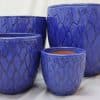 Dark blue glazed pots of various sizes with protea flower-shaped patterns on them.