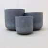 Three charcoal clay pots of various sizes against a white background.