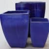 Three dark blue glazed square pots of various sizes.