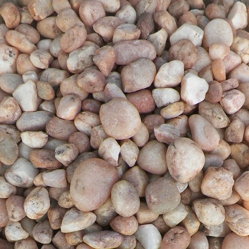 A close-up of a pile of smooth pebbles in various light earthy tone colours.