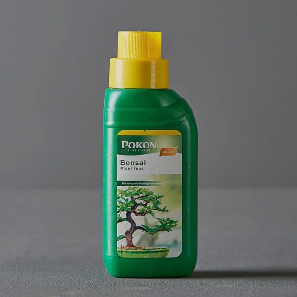 A bottle of green plant food labeled "Pokon Bonsai Plant Food."