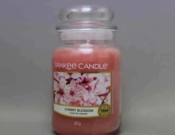 A large glass jar of Yankee Candle brand Cherry Blossom scented candle.
