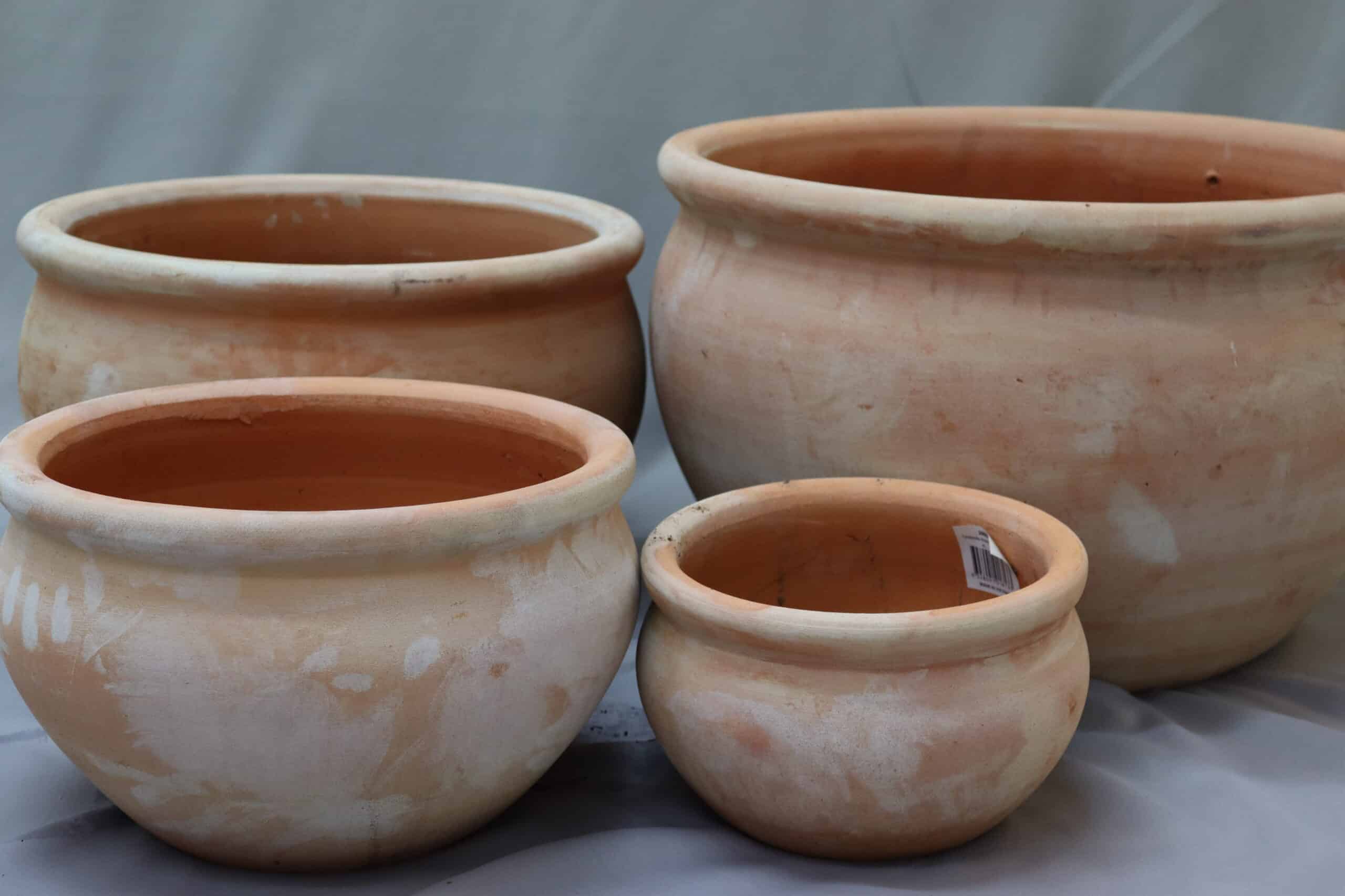 Four terracotta plant pots in different sizes and with flat rims.
