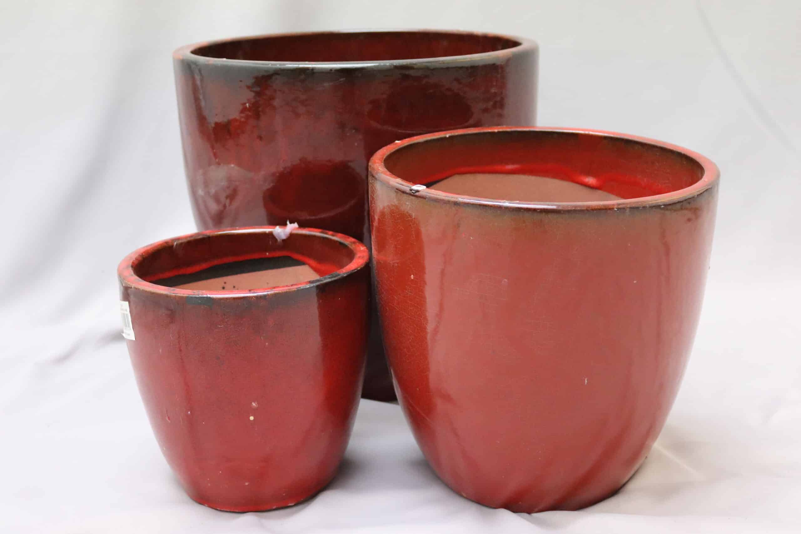 Large, medium and small glazed red egg-shaped ceramic pots.
