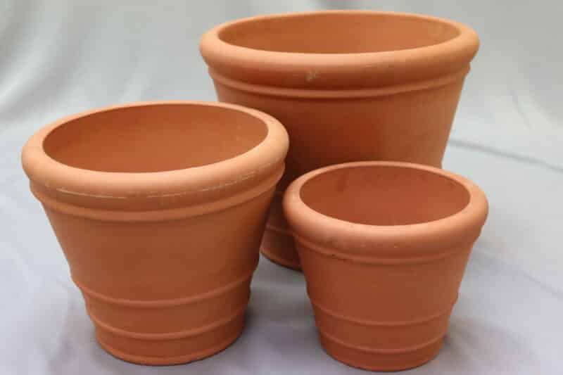 Large, medium and small round ceramic planter pots in terracotta colour.