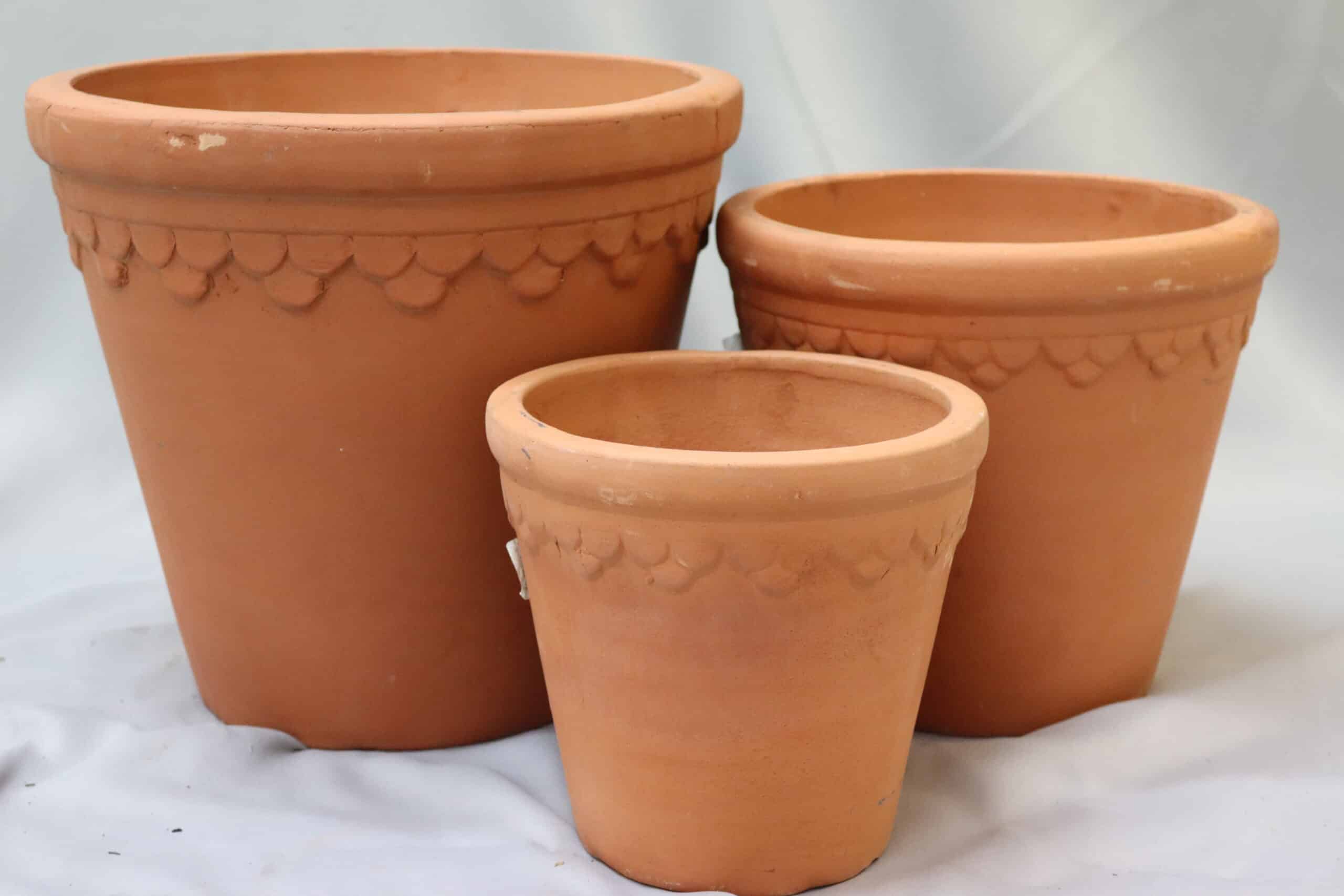 A small, medium and large terracotta plant pot with embossed pattern under the rim.