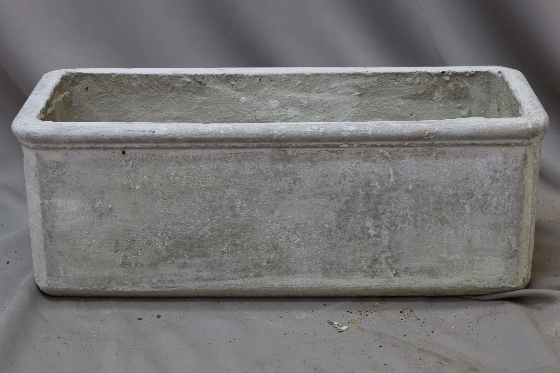 Rectangular grey concrete planter against a grey background.