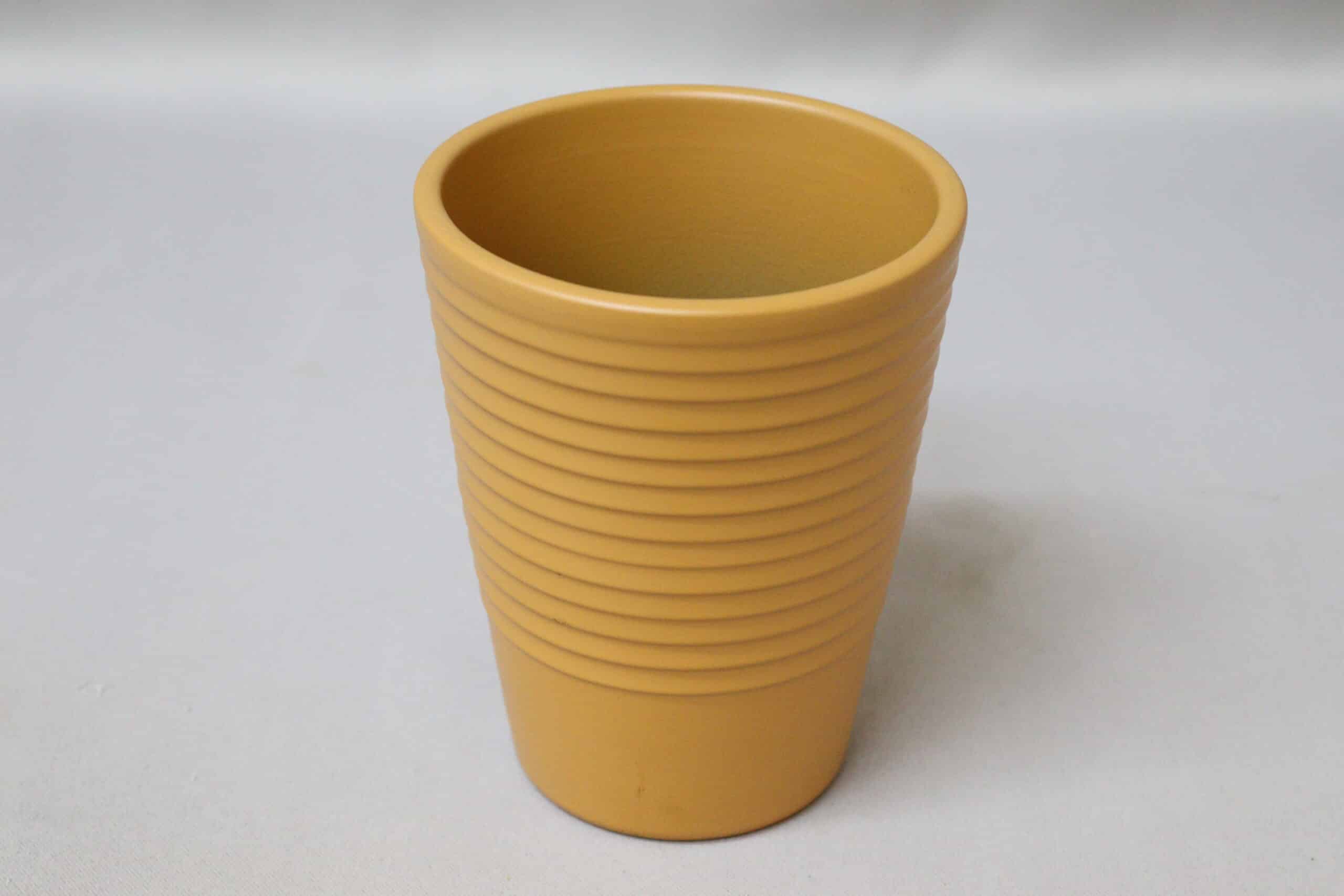 Tall, ribbed caramel-coloured pot cover for potted plants.