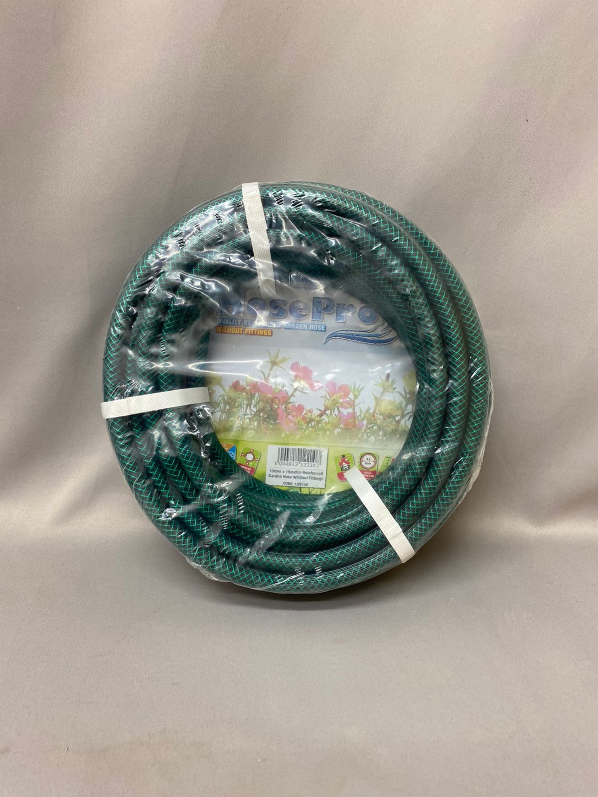 A green garden hose wrapped in plastic packaging against a plain background.